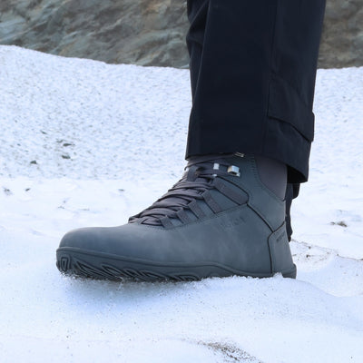 Käyttökuva pakkasharmaista Uoma Talvi 3 -vaelluskengistä lumisella rinteellä. Kuvassa korostuvat vedenpitävyys ja pitävä talvipohja.