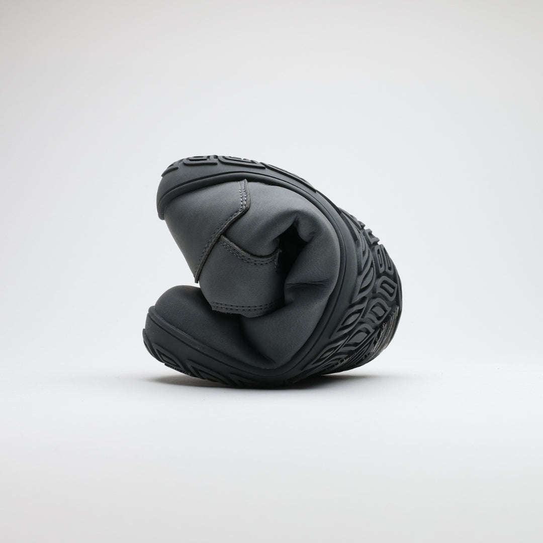 Pakkasharmaa Vaistoa Uoma Talvi 3 -kenkä rullattuna kokoon taipuisuuden havainnollistamiseksi. Kuvassa näkyy ohut ja joustava talvipohja.