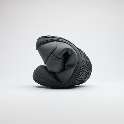 Pakkasharmaa Vaistoa Uoma Talvi 3 -kenkä rullattuna kokoon taipuisuuden havainnollistamiseksi. Kuvassa näkyy ohut ja joustava talvipohja.