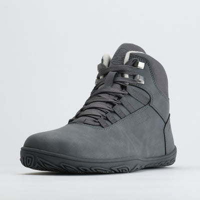 Yksi pakkasharmaa Vaistoa Uoma Talvi 3 -paljasjalkakenkä kuvattuna etuviistosta. Kuvassa korostuu vedenpitävä pinta ja leveä varvastila.