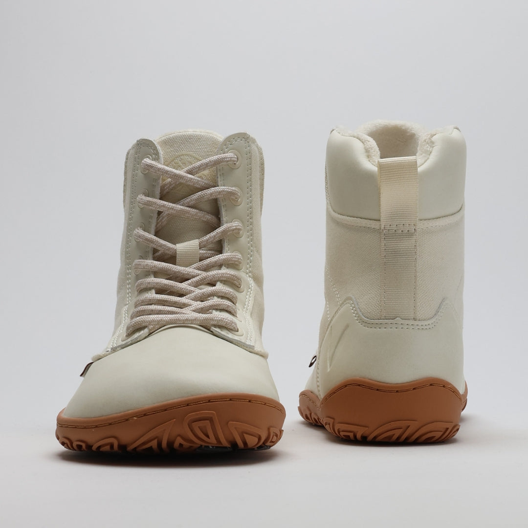 Luonnonvalkea Vaistoa Hurmos 2 -paljasjalkamaiharipari kuvattuna edestä ja takaa. Kuvassa näkyvät kengän korkea varsi, nauhoitus, pehmeä sisävuori ja ruskea ohut pohja.