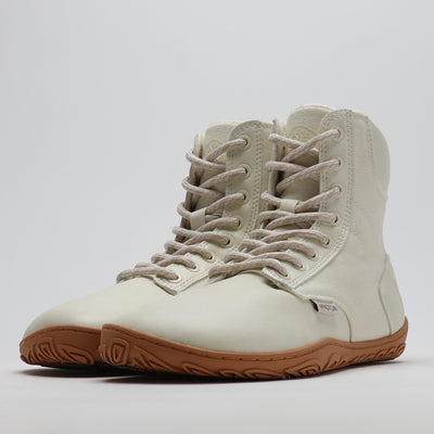 Luonnonvalkea Vaistoa Hurmos 2 -paljasjalkamaiharipari kuvattuna etuviistosta. Kevyt ja korkeavartinen talvikenkämalli, jossa on ruskea ohut pohja ja vaalea nauhoitus luonnolliseen liikkumiseen.