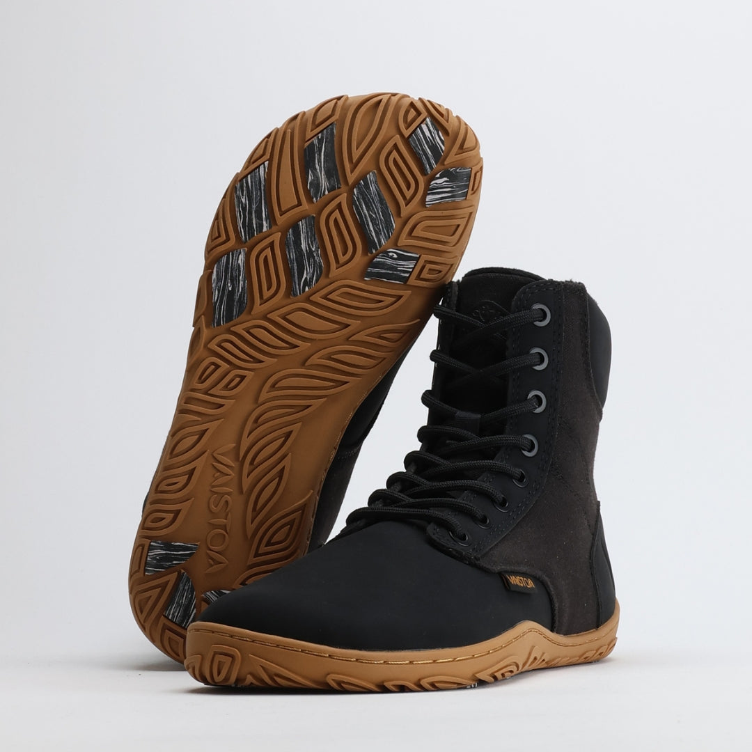 Musta Vaistoa Hurmos 2 -paljasjalkamaihari kuvattuna studiossa. Toinen kenkä nojaa toiseen, ja pohjan kitkapalat näkyvät selvästi. Kuvassa on mukana Design from Finland -merkintä.