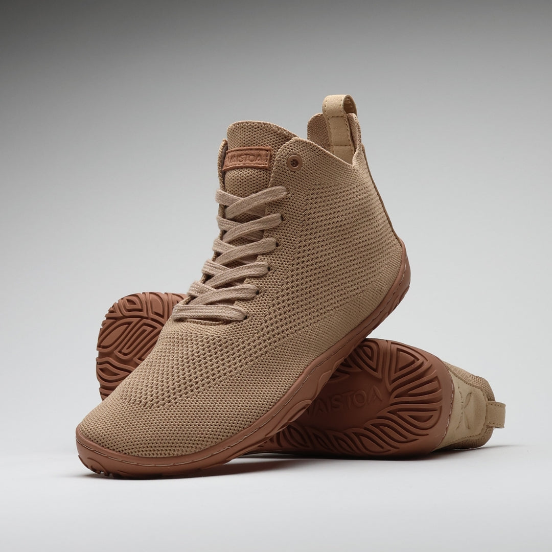 Vaistoa Iloa Mid latte – korkeavartiset paljasjalkatennarit tyylikkäästi aseteltuna: etualalla kenkä sivuviistossa, taustalla toinen kenkä pohja esillä; hengittävä neulospinta ja ohut, joustava tasapohja ilman kantakorkoa korostavat luonnollista askellusta.