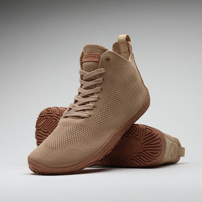 Vaistoa Iloa Mid latte – korkeavartiset paljasjalkatennarit tyylikkäästi aseteltuna: etualalla kenkä sivuviistossa, taustalla toinen kenkä pohja esillä; hengittävä neulospinta ja ohut, joustava tasapohja ilman kantakorkoa korostavat luonnollista askellusta.