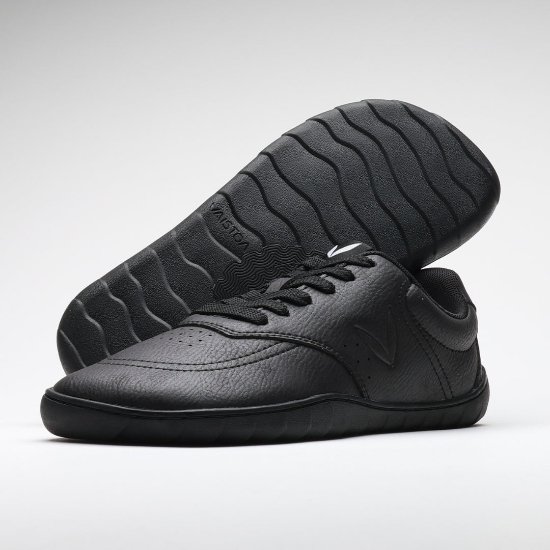 Vaistoa Katu 2 mustat paljasjalkasneakerit – minimalistinen, nahkamainen pinta ja tasainen, joustava pohja. Yksi kenkä kuvattuna pohja esillä, Design from Finland -merkintä.