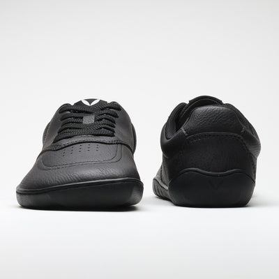 Vaistoa Katu 2 mustat paljasjalkasneakerit – kuvattuna edestä ja takaa, esittäen minimalistisen muotoilun, leveän varvastilan ja tasaisen, joustavan pohjan.