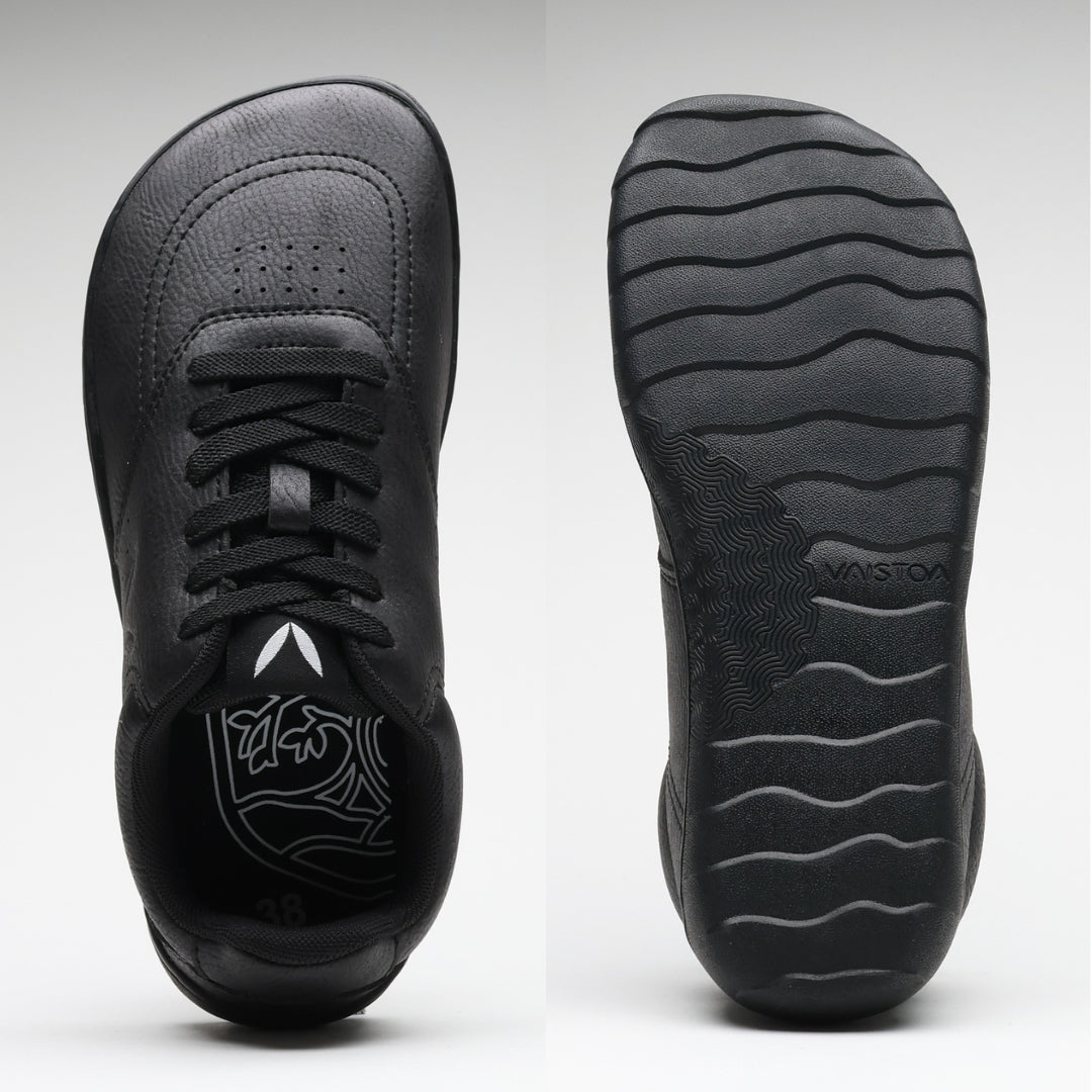 Vaistoa Katu 2 mustat paljasjalkasneakerit – ylhäältä kuvattuna näkyy leveä, jalanmuotoinen varvastila, ja pohjasta kuvattuna ohut, joustava pohja aaltoilevalla kuviolla.