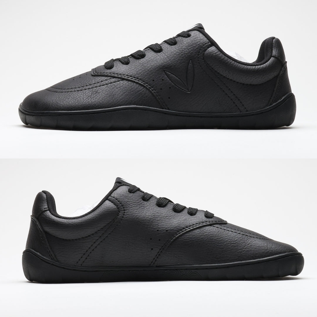 Vaistoa Katu 2 musta paljasjalkasneaker – sivuprofiilista kuvattuna molemmilta puolilta, esitellen täysin tasaisen pohjan ilman kantakorkoa luonnollisen askelluksen tukemiseksi.