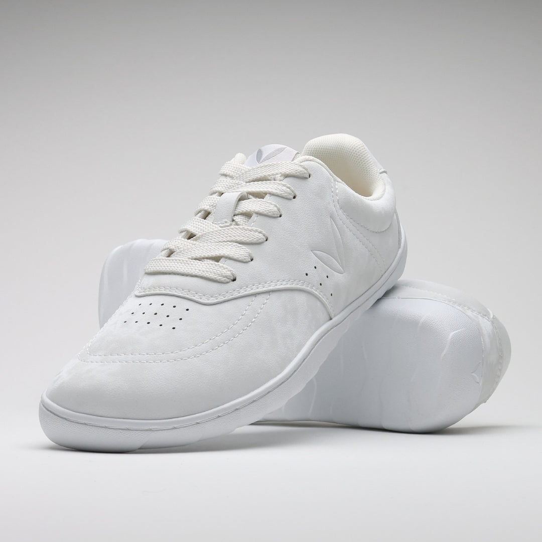 Vaistoa Katu 2 valkoiset paljasjalkasneakerit – tyylikkäästi aseteltuna niin, että toinen kenkä nojaa toisen pohjaa vasten, korostaen minimalistista muotoilua ja ohuen pohjan joustavuutta.