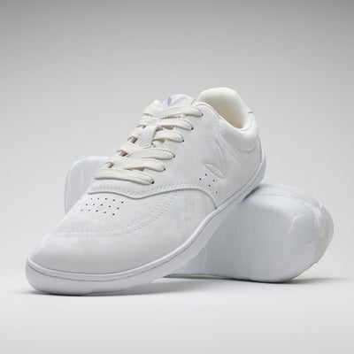 Vaistoa Katu 2 valkoiset paljasjalkasneakerit – tyylikkäästi aseteltuna niin, että toinen kenkä nojaa toisen pohjaa vasten, korostaen minimalistista muotoilua ja ohuen pohjan joustavuutta.