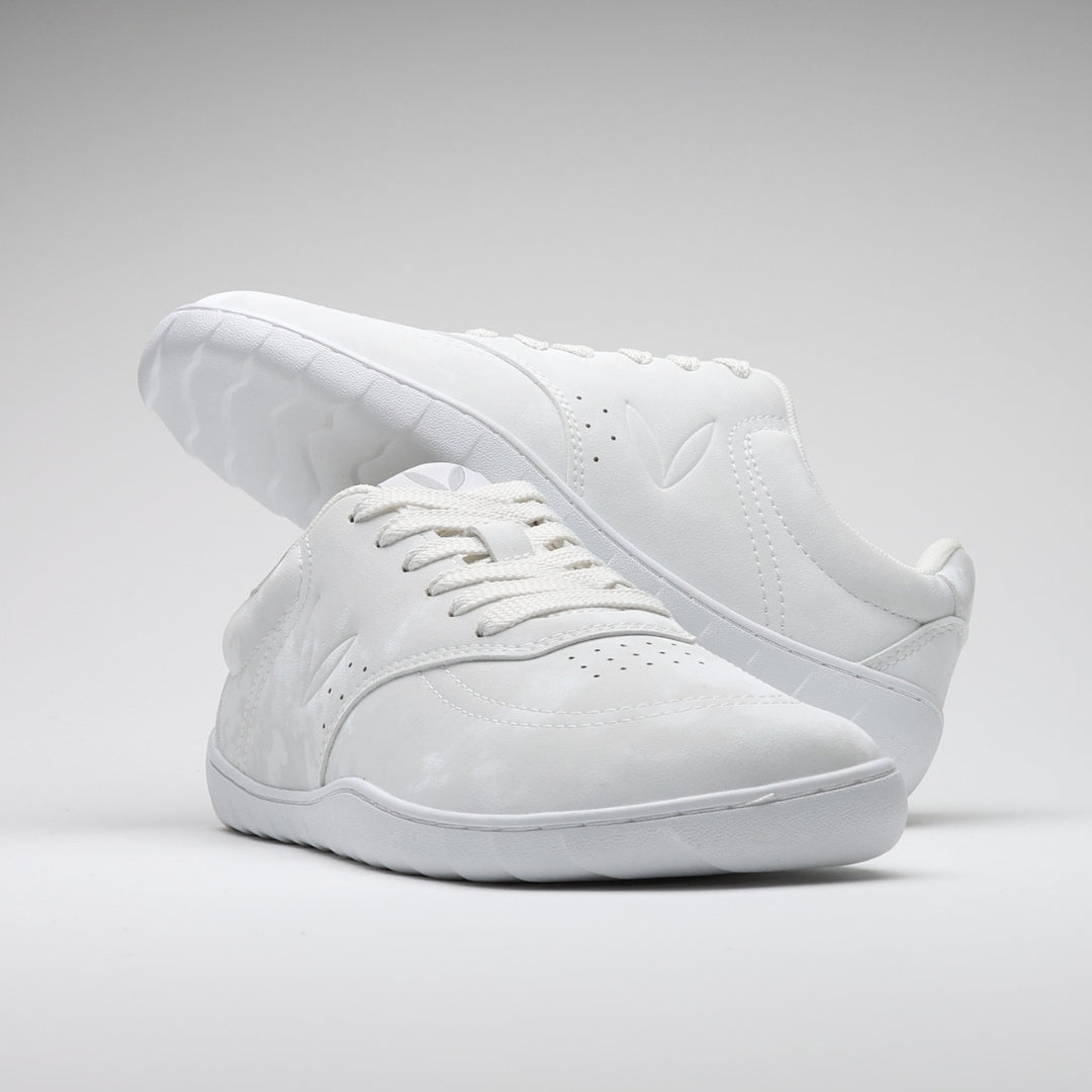 Vaistoa Katu 2 valkoiset paljasjalkasneakerit – tyylikkäästi aseteltuna niin, että toinen kenkä lepää toisen päällä, korostaen minimalistista muotoilua ja siroa siluettia.