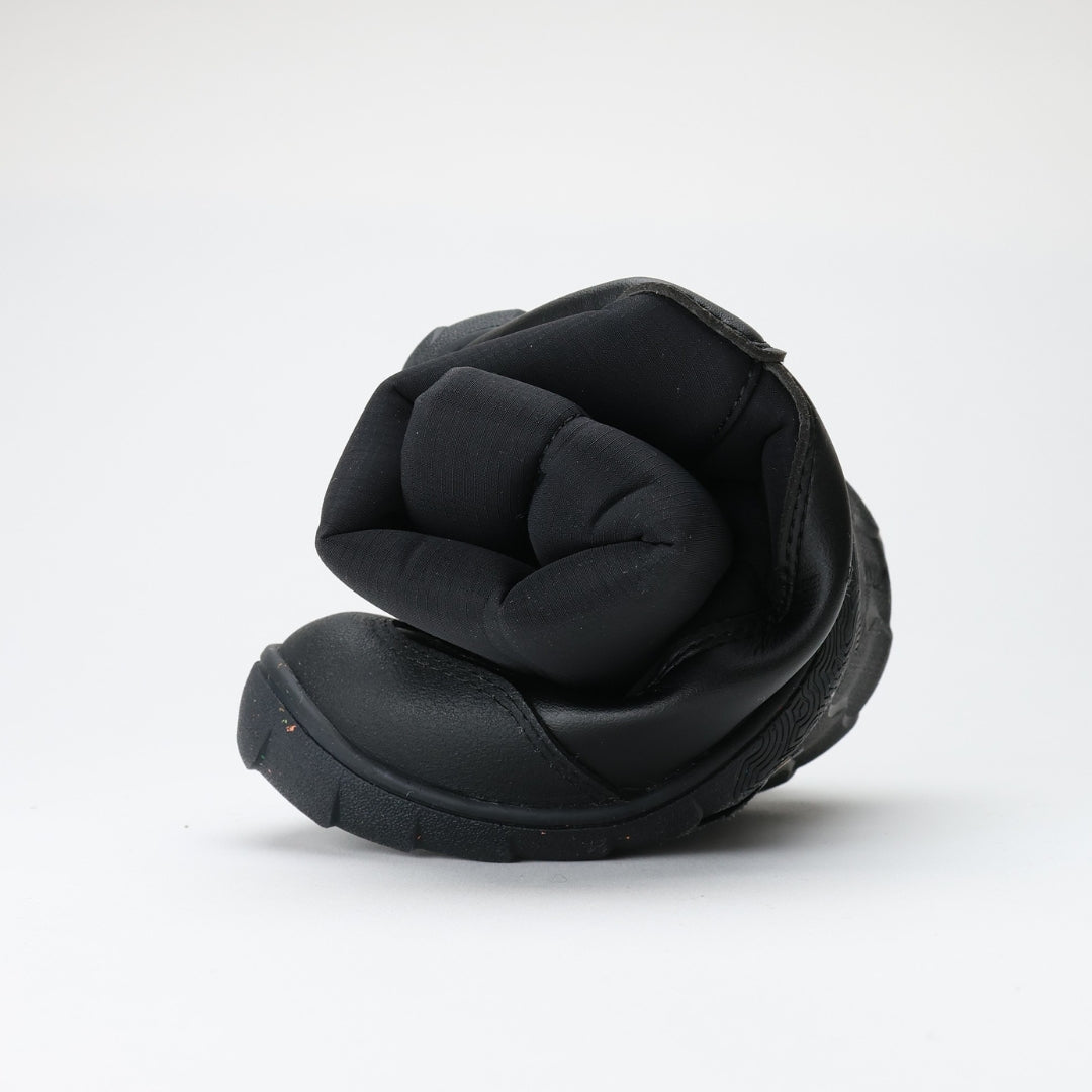 Vaistoa Kinos – lasten korkeavartiset paljasjalkakengät talveen, väri musta. Kuvassa kenkä rullattuna, korostaen ohutta ja joustavaa pohjaa.