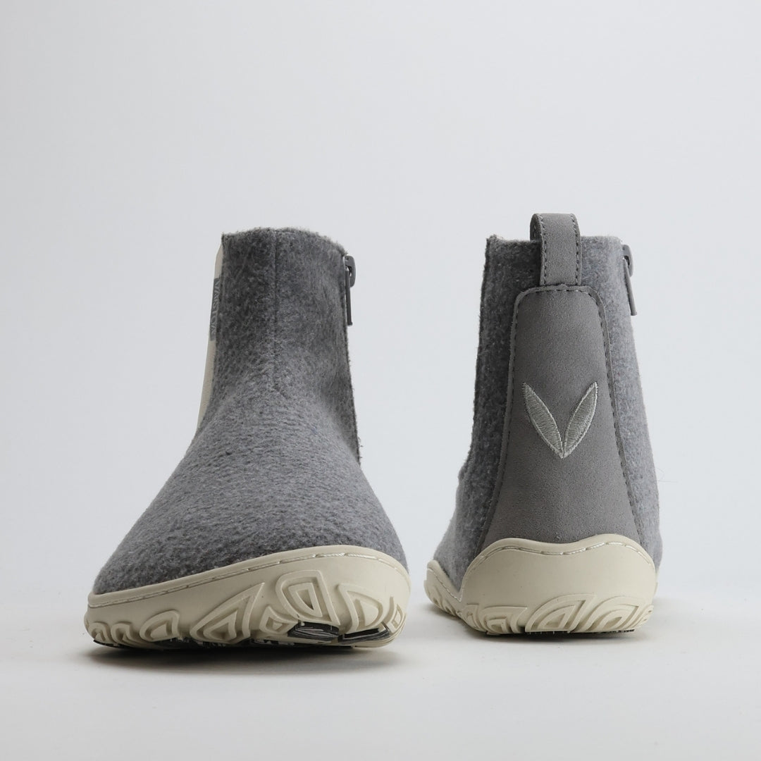 Kuva helmenharmaista Vaistoa Sulo -huopanilkkureista edestä ja takaa. Vasemmassa kengässä näkyy leveä varvastila ja oikeassa takasaumassa Vaistoa-logon lehtisymboli.