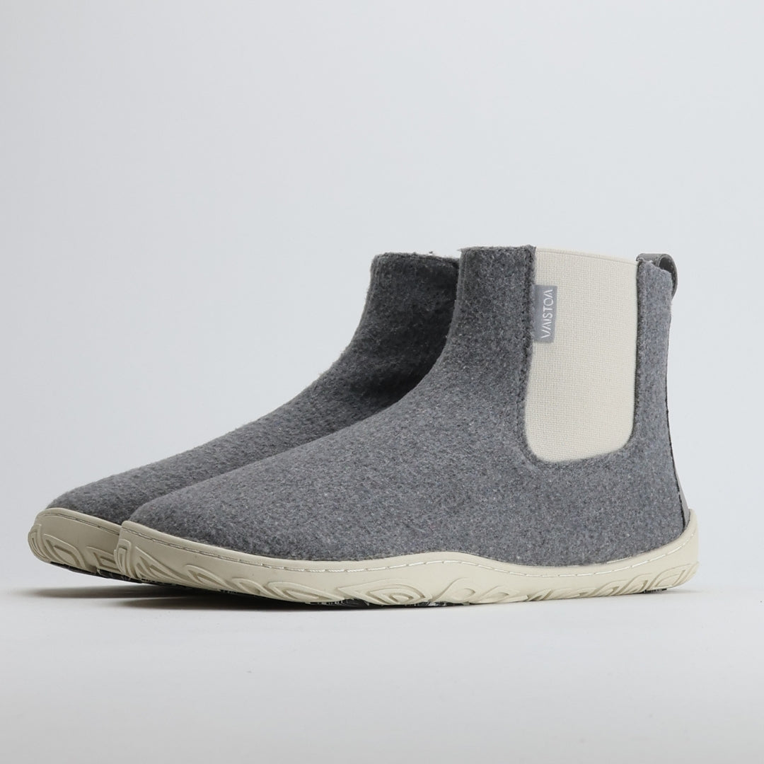 Kaksi helmenharmaata Vaistoa Sulo -huopanilkkuria on kuvattu etuviistosta. Kuvassa korostuu kengän minimalistinen muotoilu, vaalea joustoresori ja kevyt Vaistoa Pitoa™ -talvipohja.