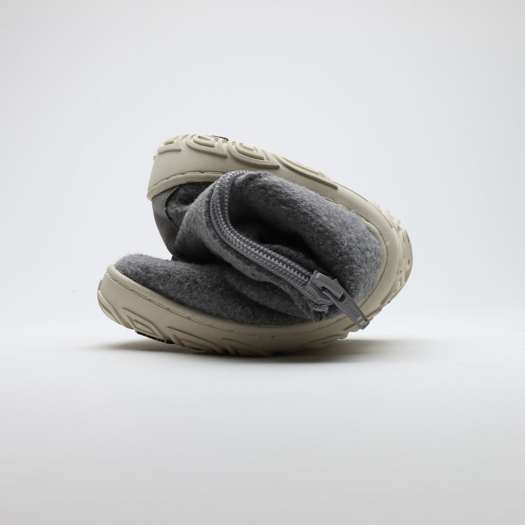 Kuva näyttää helmenharmaan Vaistoa Sulo -huopanilkkurin rullattuna kokoon. Kuvassa korostuu kengän ohut ja joustava pohja, joka mahdollistaa luonnollisen liikkeen ja paljasjalkatuntuman.