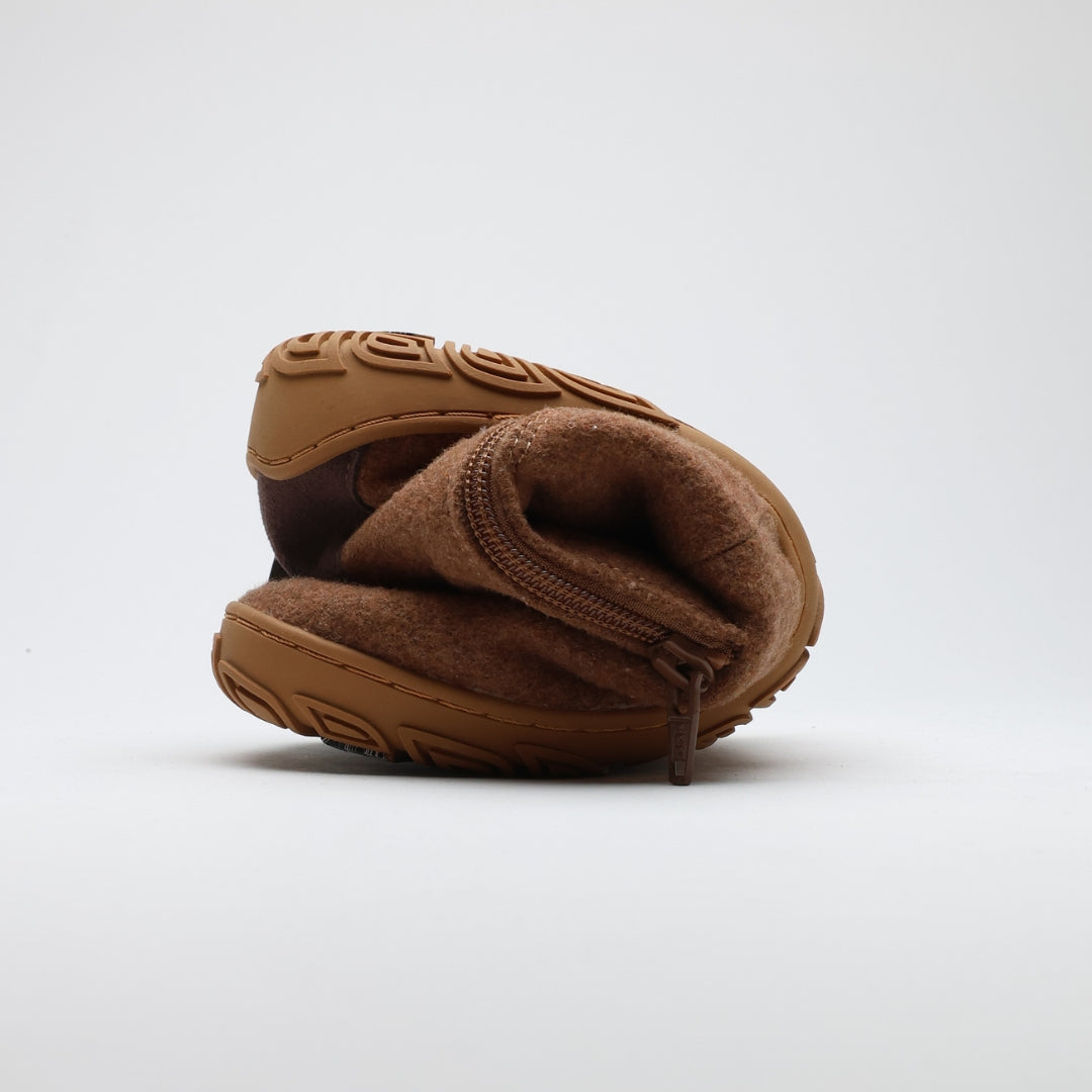 Kuva esittää paahdetun mantelin väristä Vaistoa Sulo -huopanilkkuria, joka on rullattu kokoon korostaen kengän ohutta ja erittäin taipuisaa pohjaa. Vetoketju näkyy sivulla, mikä kertoo helppokäyttöisyydestä.