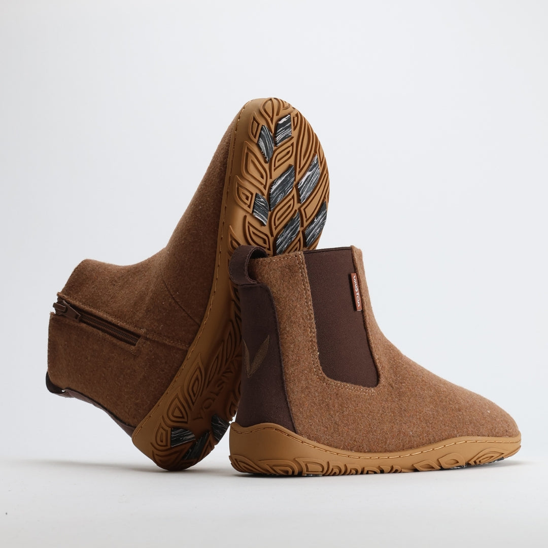 Kaksi paahdetun mantelin väristä Vaistoa Sulo -huopanilkkuria nojaa toisiinsa niin, että pohjan kuviointi ja kitkapalat näkyvät selvästi. Kuva korostaa Vaistoa Pitoa™ -talvipohjan joustavuutta ja pitoa liukkaalla alustalla.