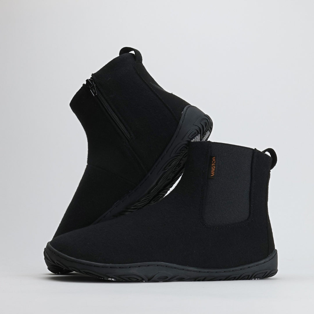 Kaksi samettisen mustaa Vaistoa Sulo -huopanilkkuria seisovat vierekkäin valkoisella taustalla. Toinen kenkä nojaa toisen varteen, paljastaen joustavan Vaistoa Pitoa™ -talvipohjan ja minimalistisen muotoilun. Kuvan oikeassa yläkulmassa näkyy Design from Finland -merkki, joka kertoo kotimaisesta suunnittelusta.