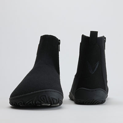 Kuva samettisen mustista Vaistoa Sulo – huopanilkkureista edestä ja takaa. Vasemmassa kengässä näkyy leveä varvastila, oikeassa takana Vaistoa-logon lehtisymboli, joka korostaa minimalistista muotoilua.