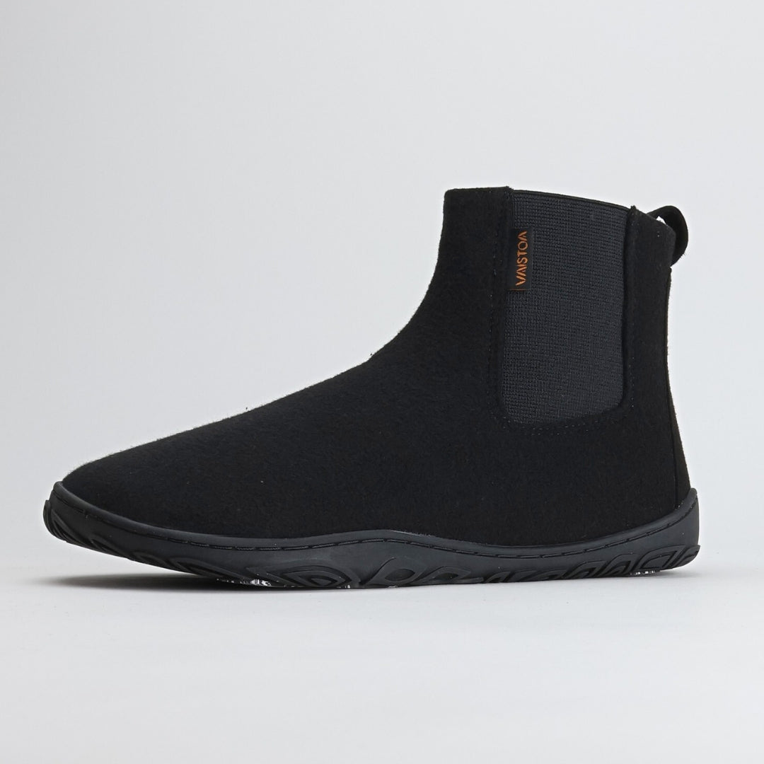 Yksittäinen samettisen musta Vaistoa Sulo – huopanilkkuri kuvattuna etuviistosta. Kuvassa näkyy kengän pehmeä huopapinta, luonnollinen varvastila ja kevyesti kaareutuva Vaistoa Pitoa™ – pohja, joka tukee jalan luonnollista liikettä.