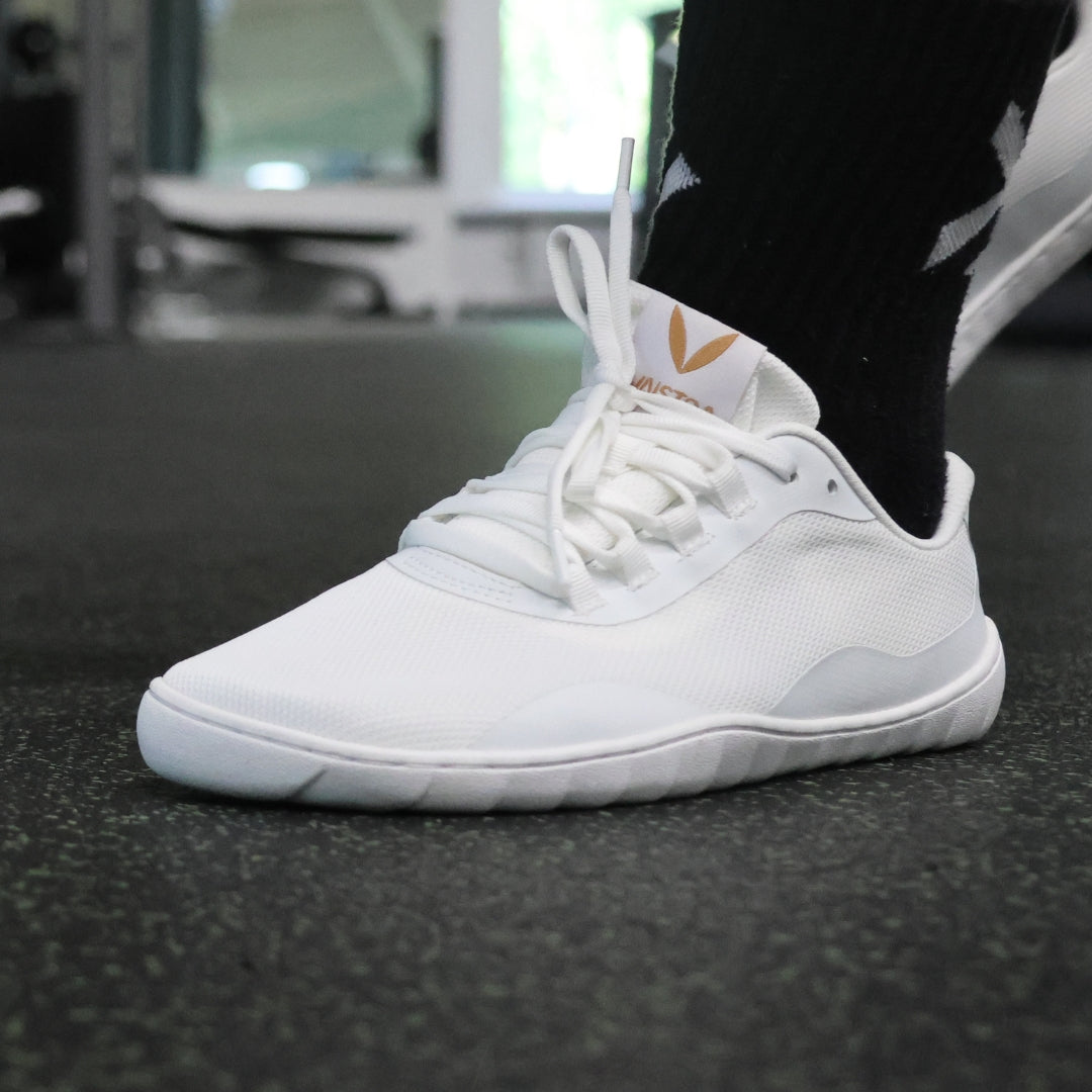 Vaistoa Tahto valkoiset paljasjalkasalikengät salikäytössä – ohut ja joustava pohja lisää vakautta ja tasapainoa painonnostossa ja toiminnallisessa harjoittelussa.