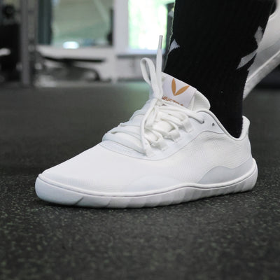 Vaistoa Tahto valkoiset paljasjalkasalikengät salikäytössä – ohut ja joustava pohja lisää vakautta ja tasapainoa painonnostossa ja toiminnallisessa harjoittelussa.