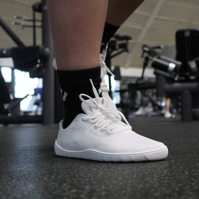 Vaistoa Tahto valkoiset paljasjalkasalikengät salilla – minimalistinen muotoilu, leveä varvastila ja matala pohja tukevat luonnollista jalkaterän asentoa.