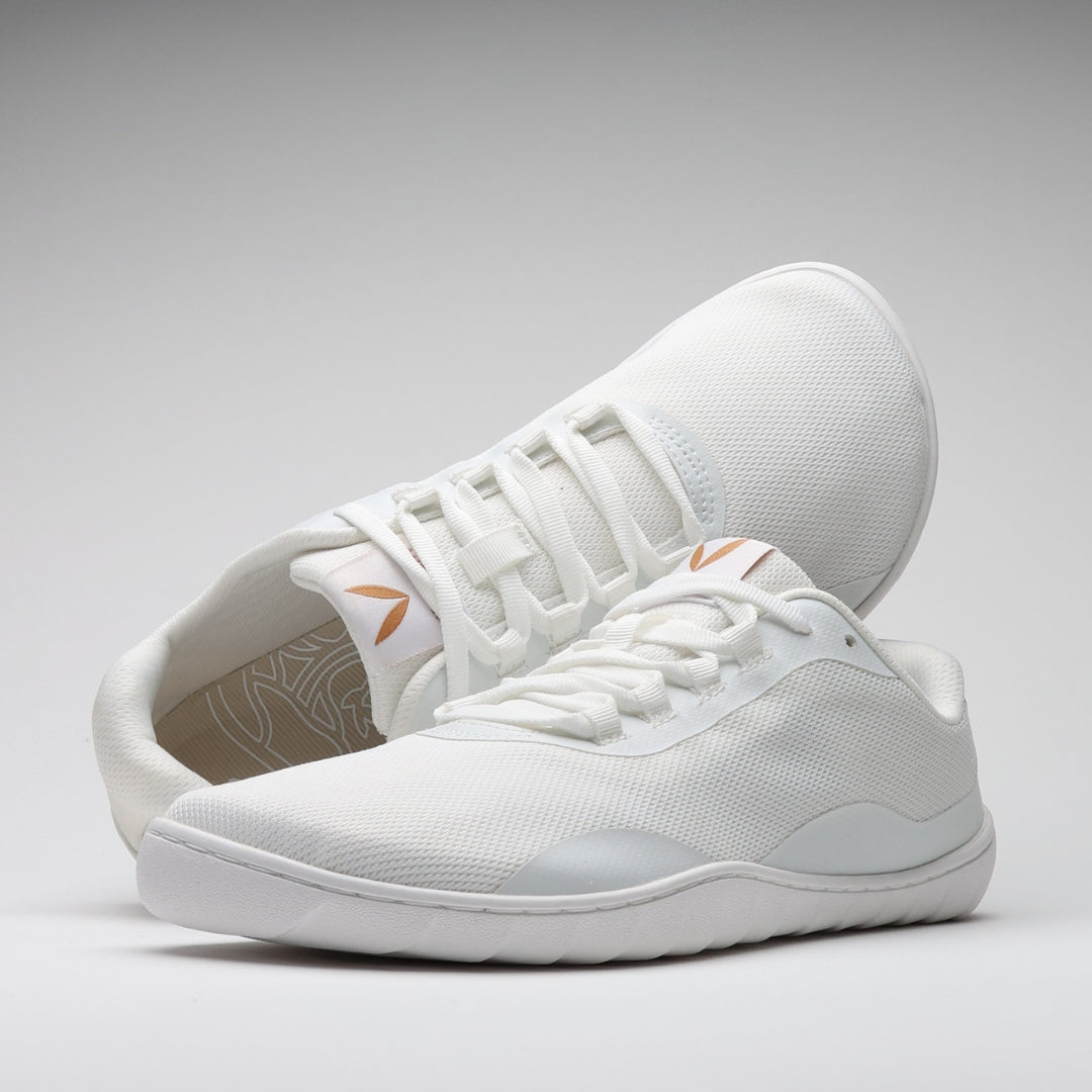 Vaistoa Tahto valkoiset paljasjalkasalikengät – etuviistosta kuvattu kenkäpari, joista taaempi on aseteltu tyylikkäästi nojaamaan etummaisen kengän kantapäähän. Asetelma korostaa kengän varvastilaa ja nauhoitusta, minimalistinen muotoilu ja ohut pohja tukevat luonnollista liikkumista.