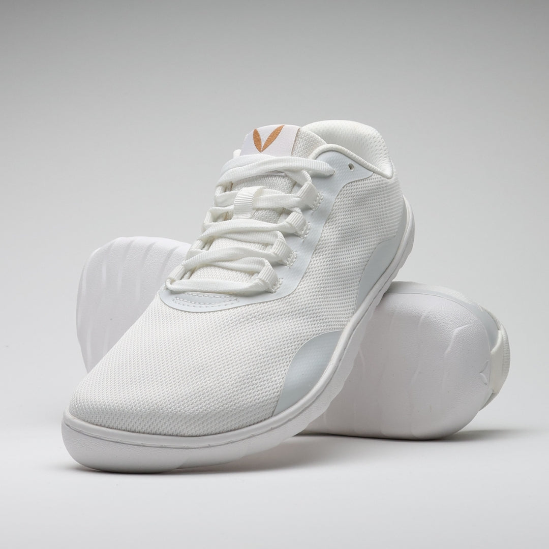 Vaistoa Tahto valkoinen paljasjalkasalikenkä – oikea kenkä kuvattuna pystyssä nojaamassa toisen kengän pohjaan, tuoden esille kengän varvastilan, joustavan pohjan ja minimalistisen muotoilun.