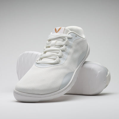 Vaistoa Tahto valkoinen paljasjalkasalikenkä – oikea kenkä kuvattuna pystyssä nojaamassa toisen kengän pohjaan, tuoden esille kengän varvastilan, joustavan pohjan ja minimalistisen muotoilun.