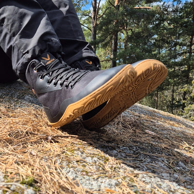 vaistoa tuohi paljasjalkaretkeilykengät musta kayttokuva kevat istuen kalliollalla auringon paisteessa